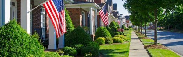 Mature street trees line the sidewalk in front of brick homes in an established Northern Virginia neighborhood.